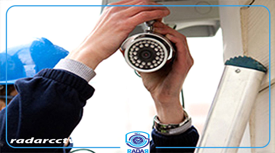 فردی در حال تعمیر دوربین مداربسته برای پارکینگ